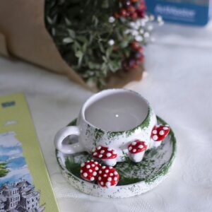 Whimsical ceramic teacup with red and white mushroom accents on a saucer.